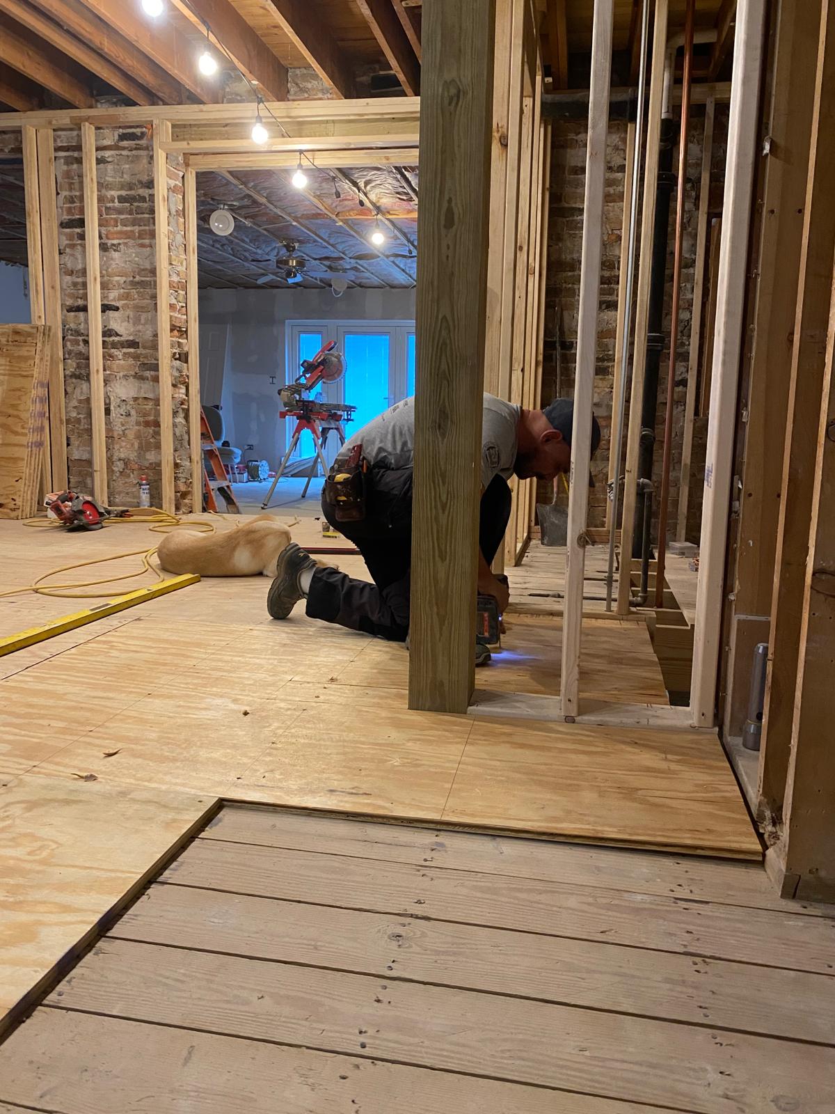 Construction worker installing wooden framing and flooring during a residential remodeling project, showcasing precision and craftsmanship by SGC Constructor.